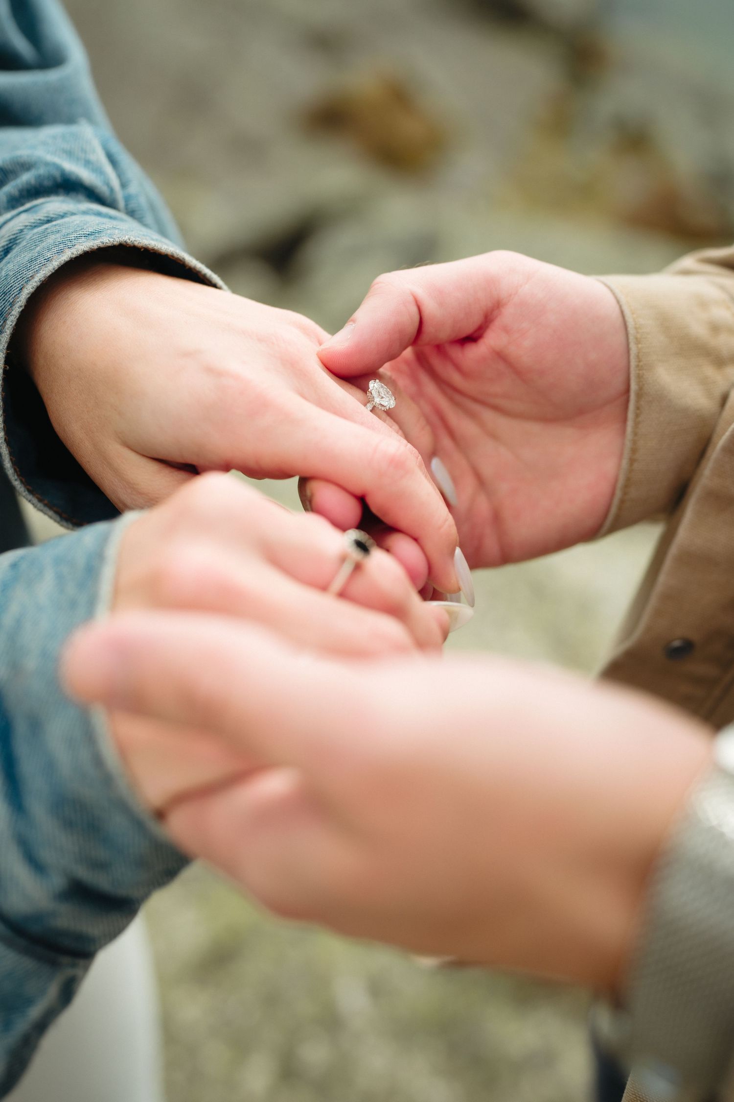 Close-up of a person placing a diamond engagement ring on their partner's finger during a romantic proposal.
