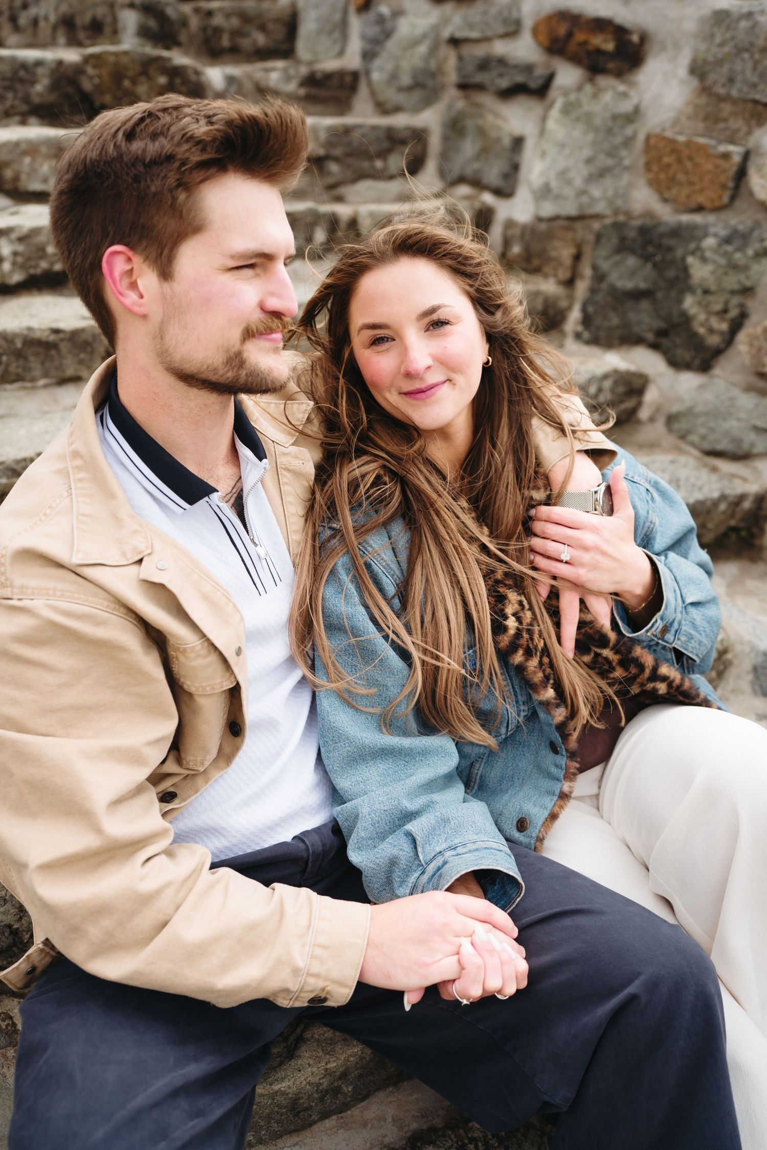 Couple sitting together on stone steps holding hands and smiling warmly.