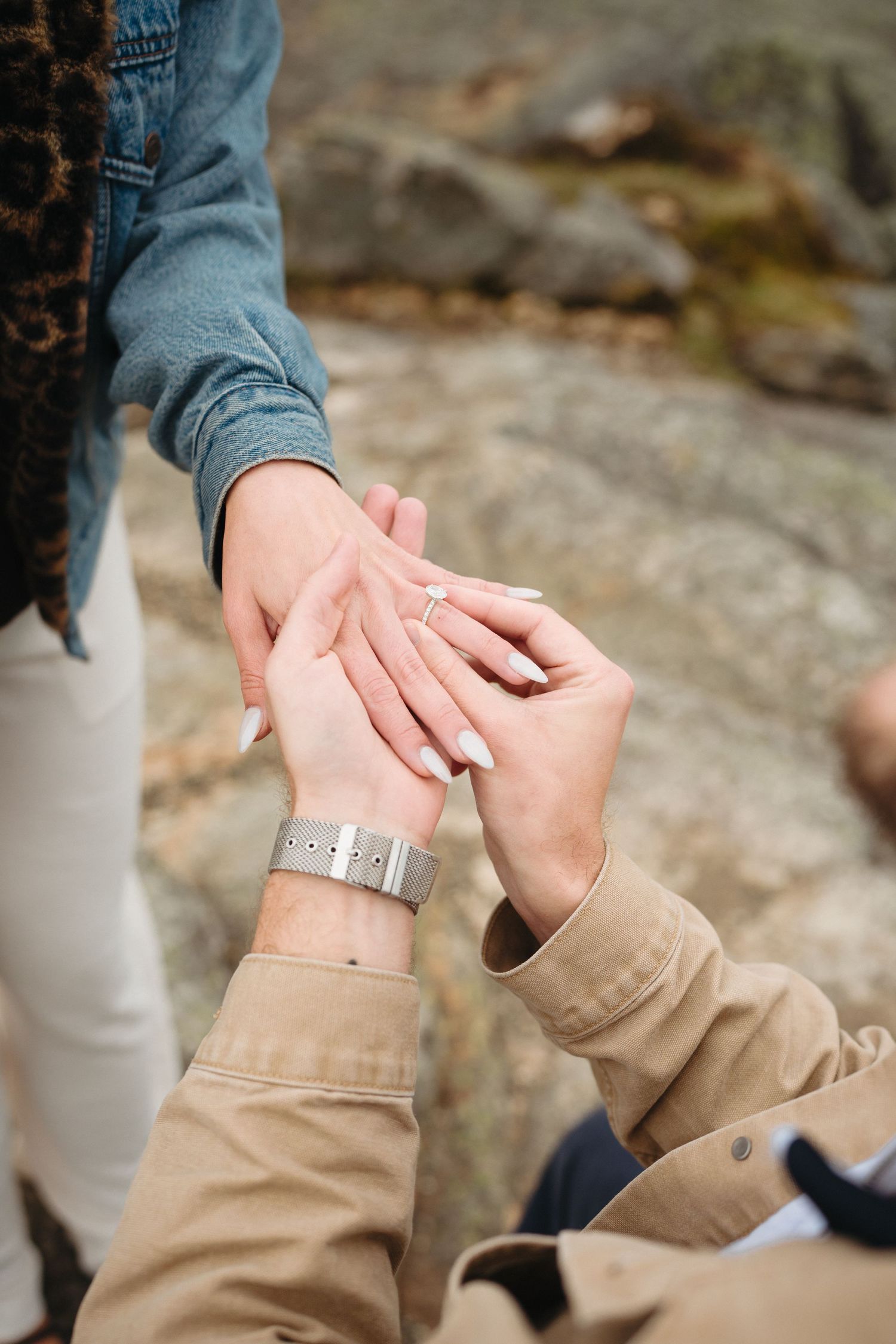 Close-up of man placing engagement ring on womans finger during proposal.