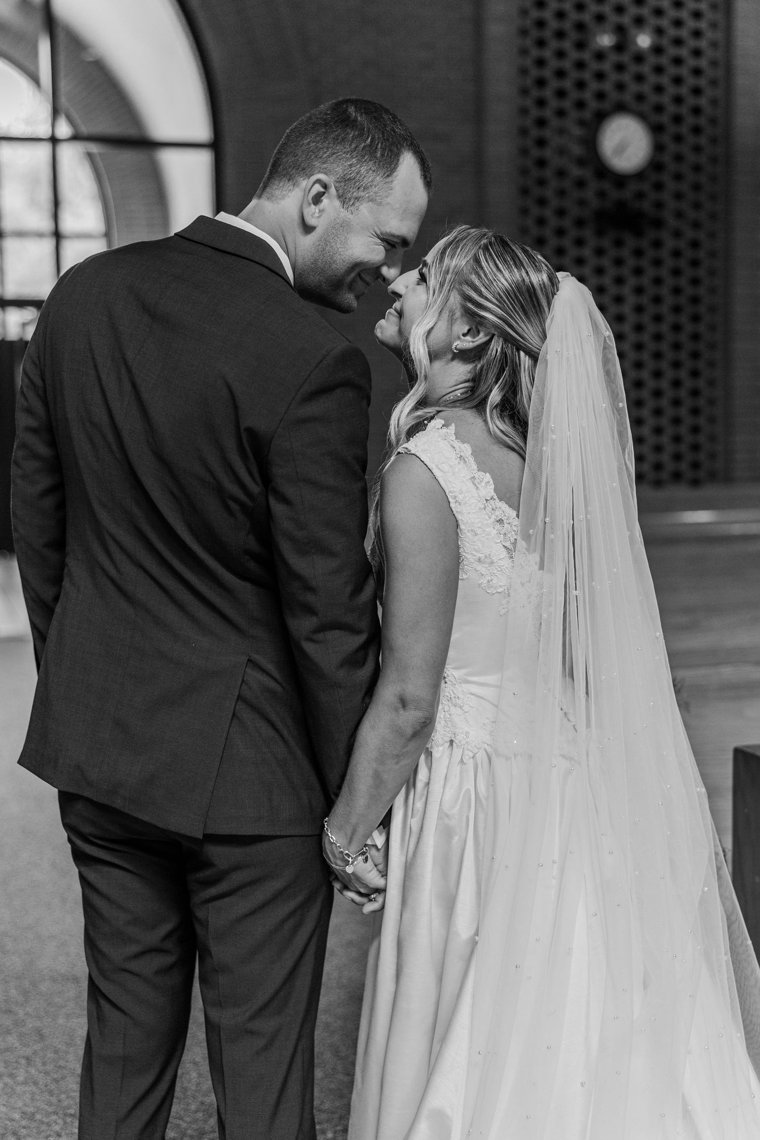 Black and white photo of a bride and groom holding hands and sharing an intimate moment on their wedding day.