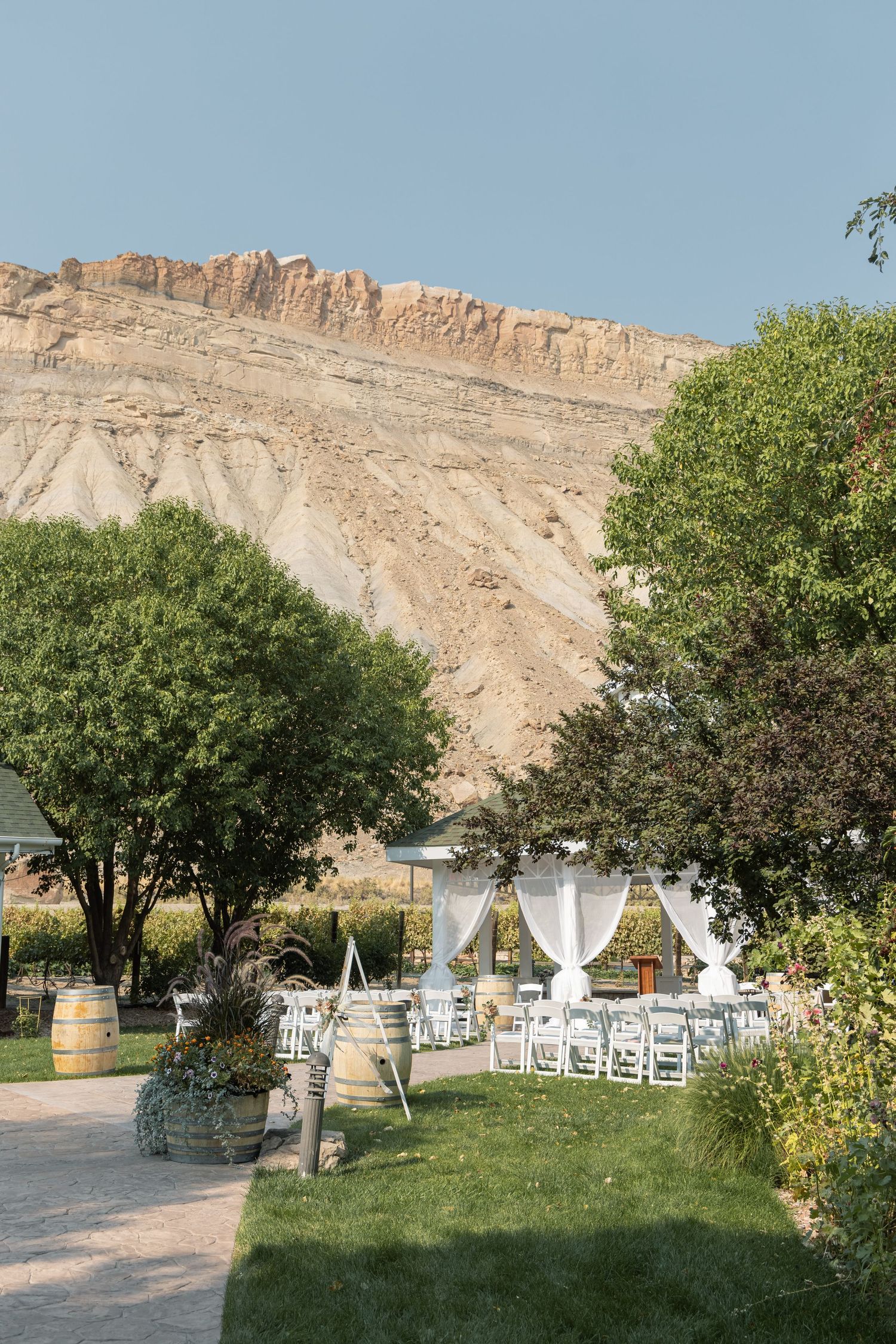 Outdoor wedding venue with white drapes and chairs set against a dramatic sandstone cliff backdrop.