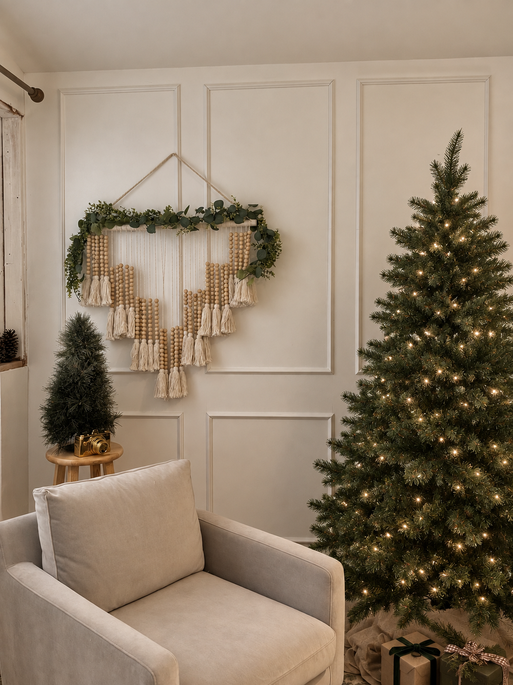 Cozy Christmas living room with lit tree, beaded wall hanging, garland, and neutral armchair in white paneled room.