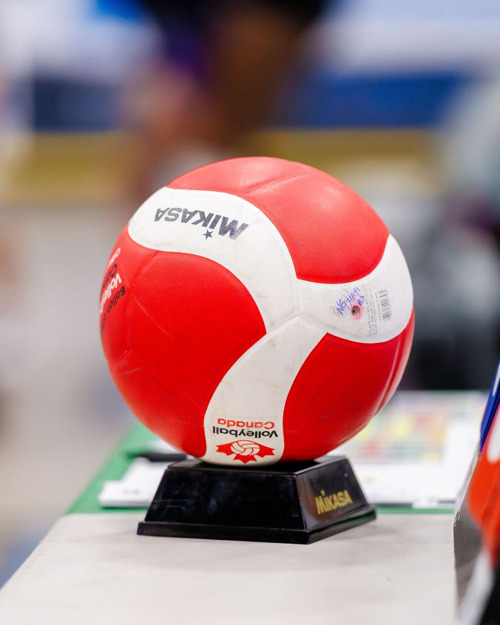 Red and white Mikasa volleyball on a display stand at a volleyball Canada tournament.
