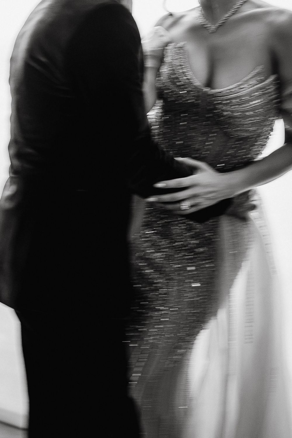 Black and white photo of a couple dancing, woman in elegant sequined gown, man in dark suit.