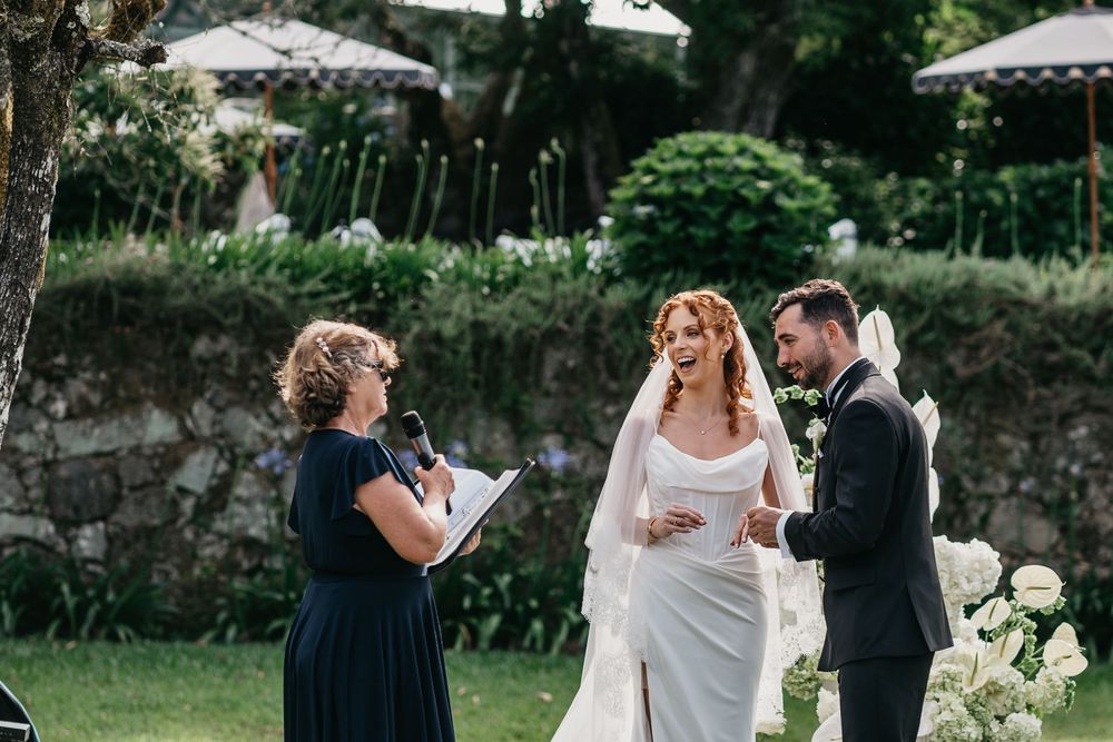 Bride and groom exchanging vows outdoors with officiant during elegant garden wedding ceremony.