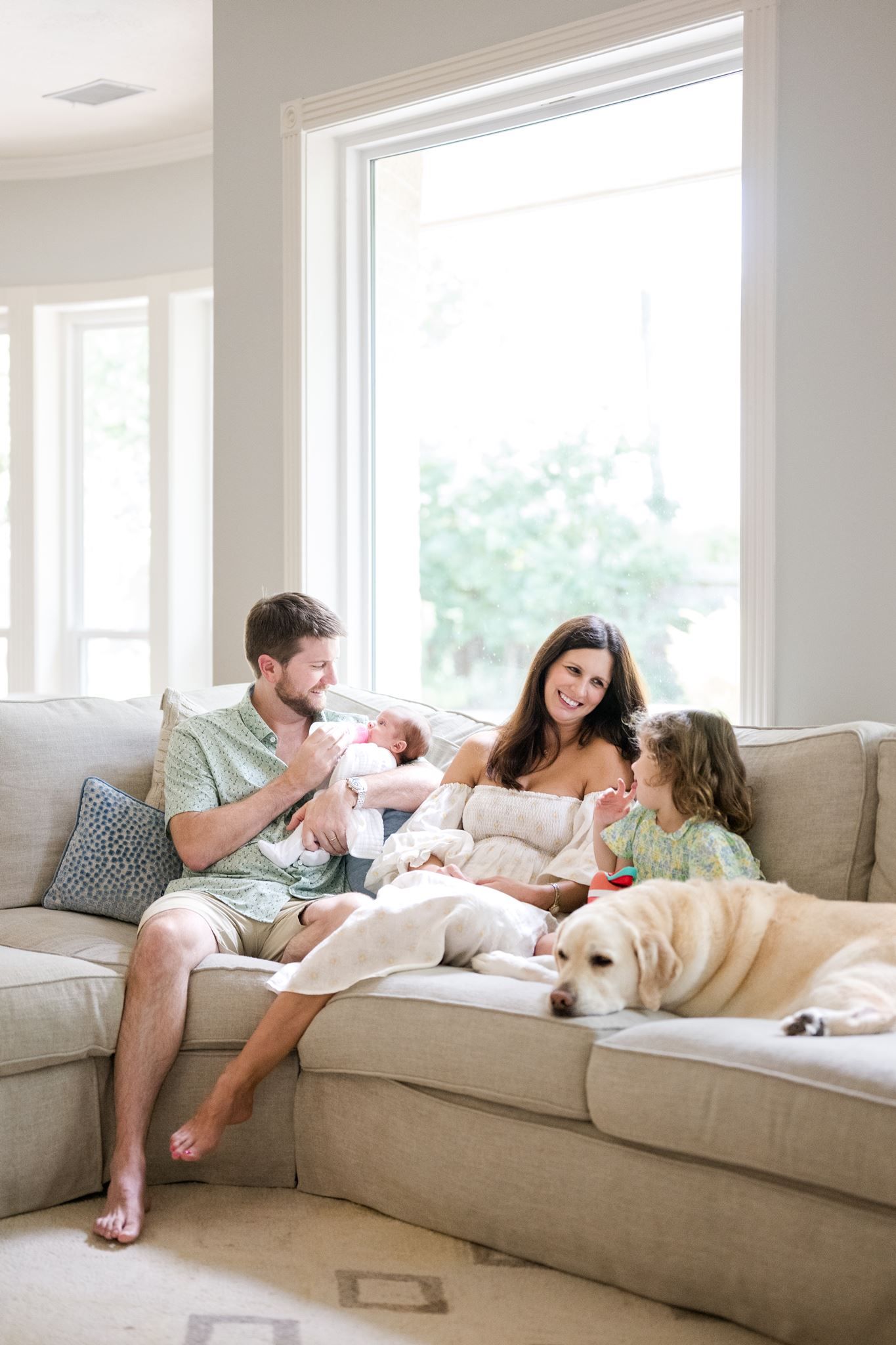 Parents cuddling their newborn on the sofa during an in-home newborn photography session