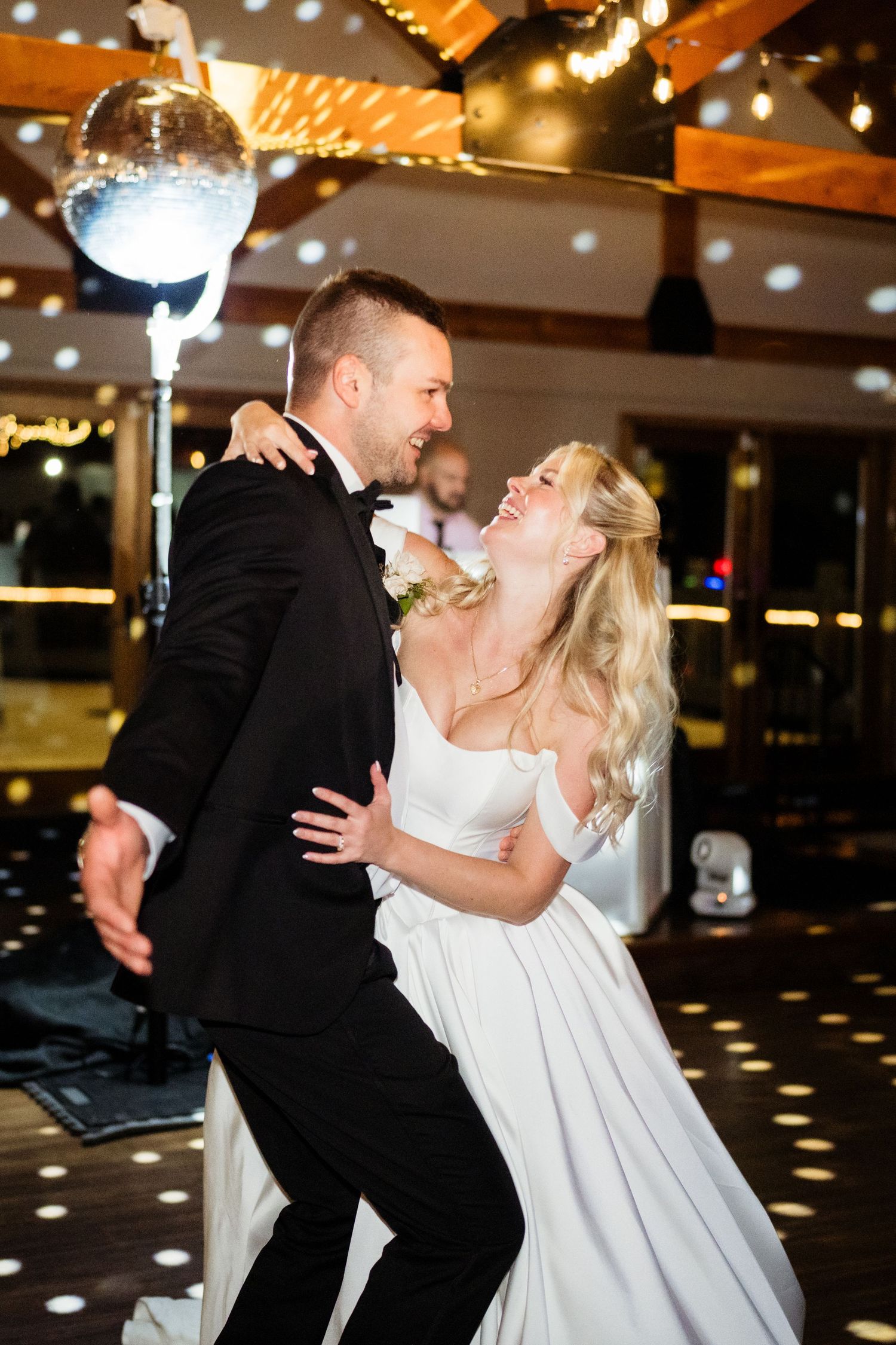Bride and groom sharing their first dance under a disco ball at a romantic wedding reception.