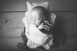 Black & white newborn photo, baby boy wrapped in white holding tiny Bible newborn pictures; best photographer Lex, SC