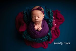 Luxury newborn photography Lexington, SC; professional portrait studio; newborn baby girl jewel-tone photos; purple wrap with blue and pink