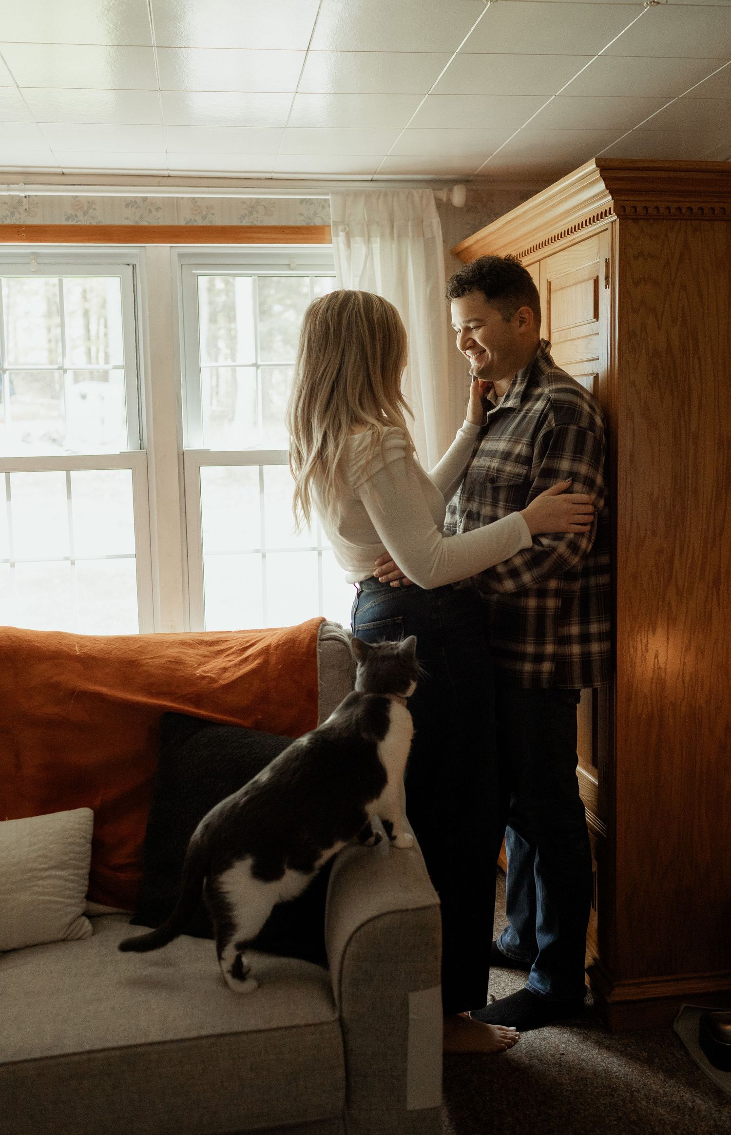 A relaxed family moment on a white bed with neutral decor and natural lighting.