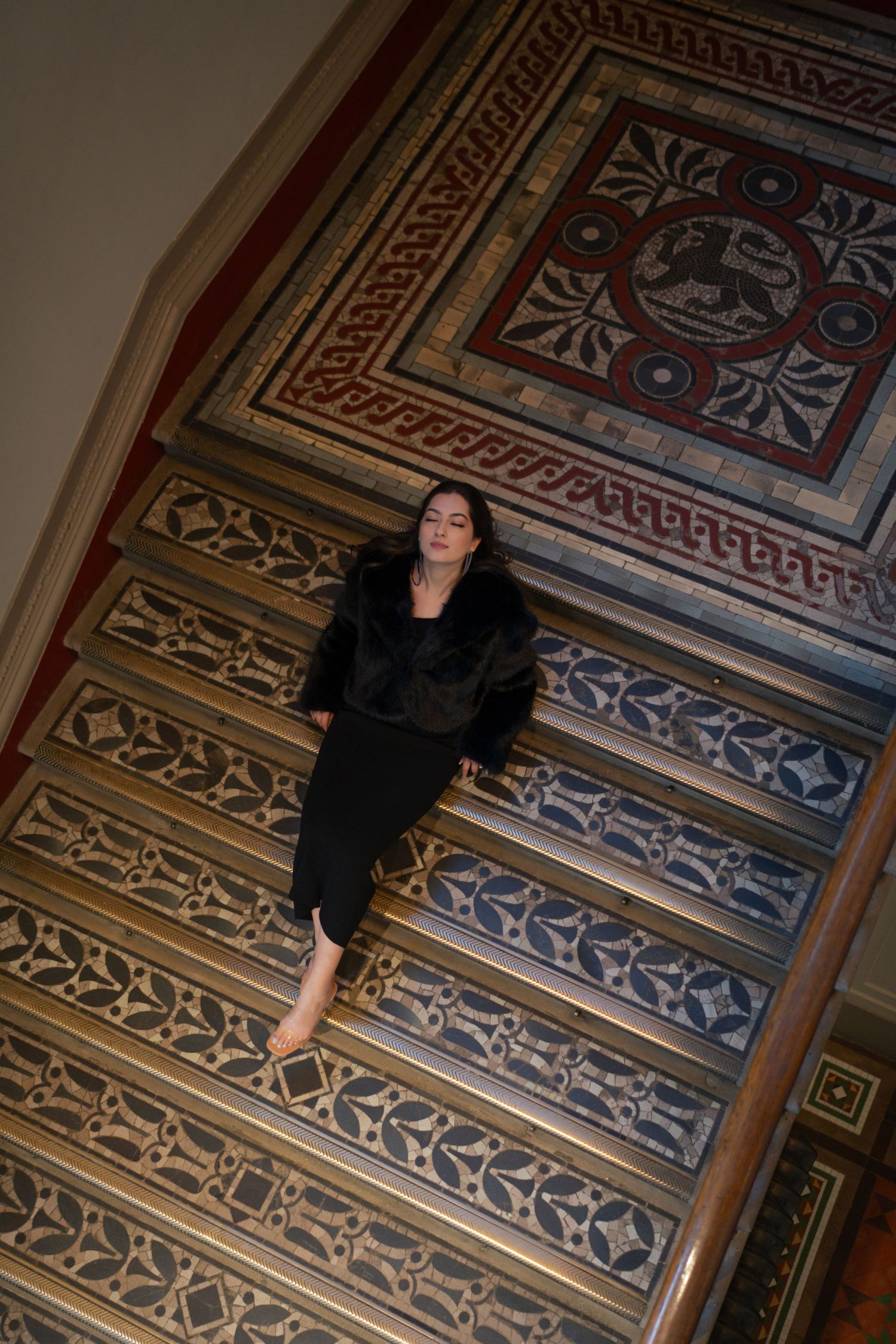 Person in black outfit lying on decorative patterned floor with geometric designs.