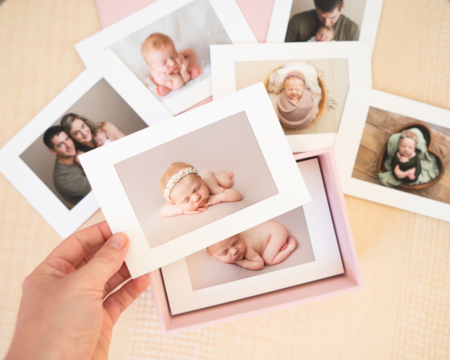 Collection of professional newborn portrait prints being held in hand.