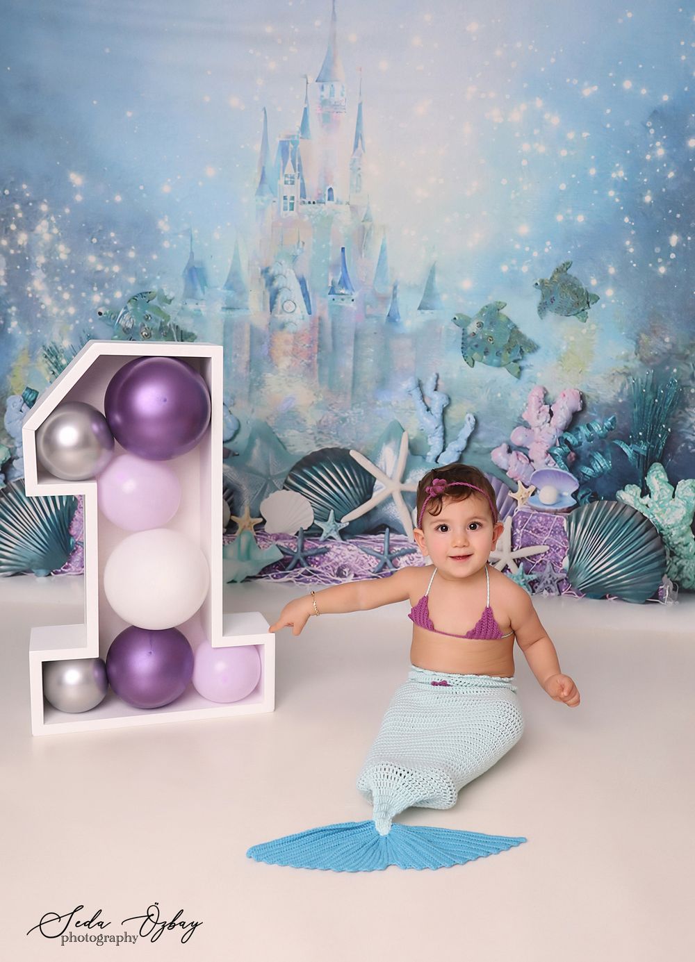 Magical mermaid themed photo setup with purple ornaments and coastal decorations.