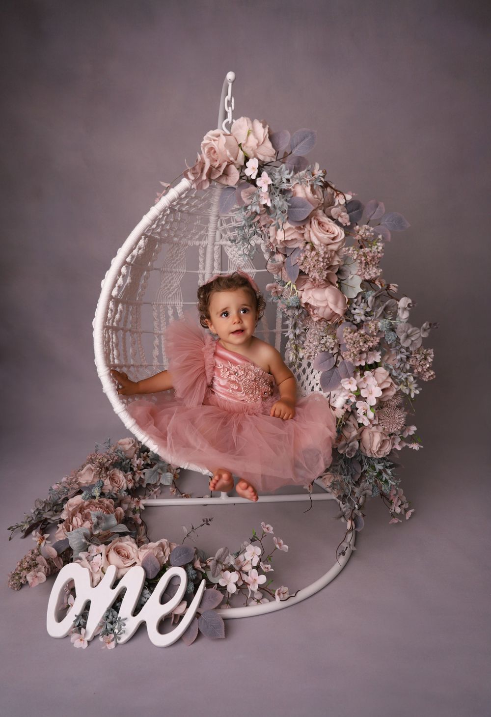 Elegant pink floral setup with white vintage bathtub and decorative number one for milestone photos.