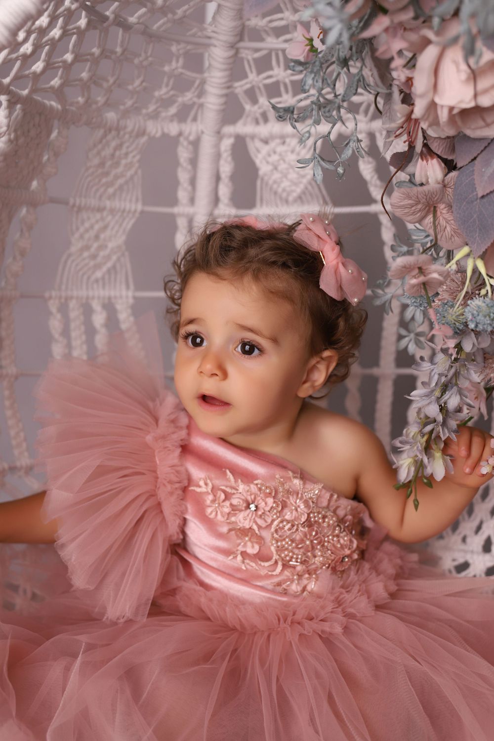 Dreamy pink tulle dress against grey backdrop with silver floral decorations.