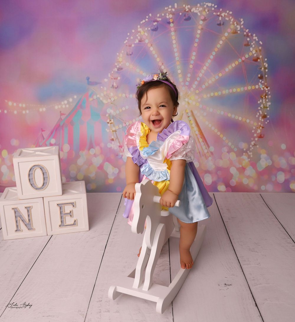 Whimsical first birthday setup with sparkling lights and white block numbers on wooden floor.