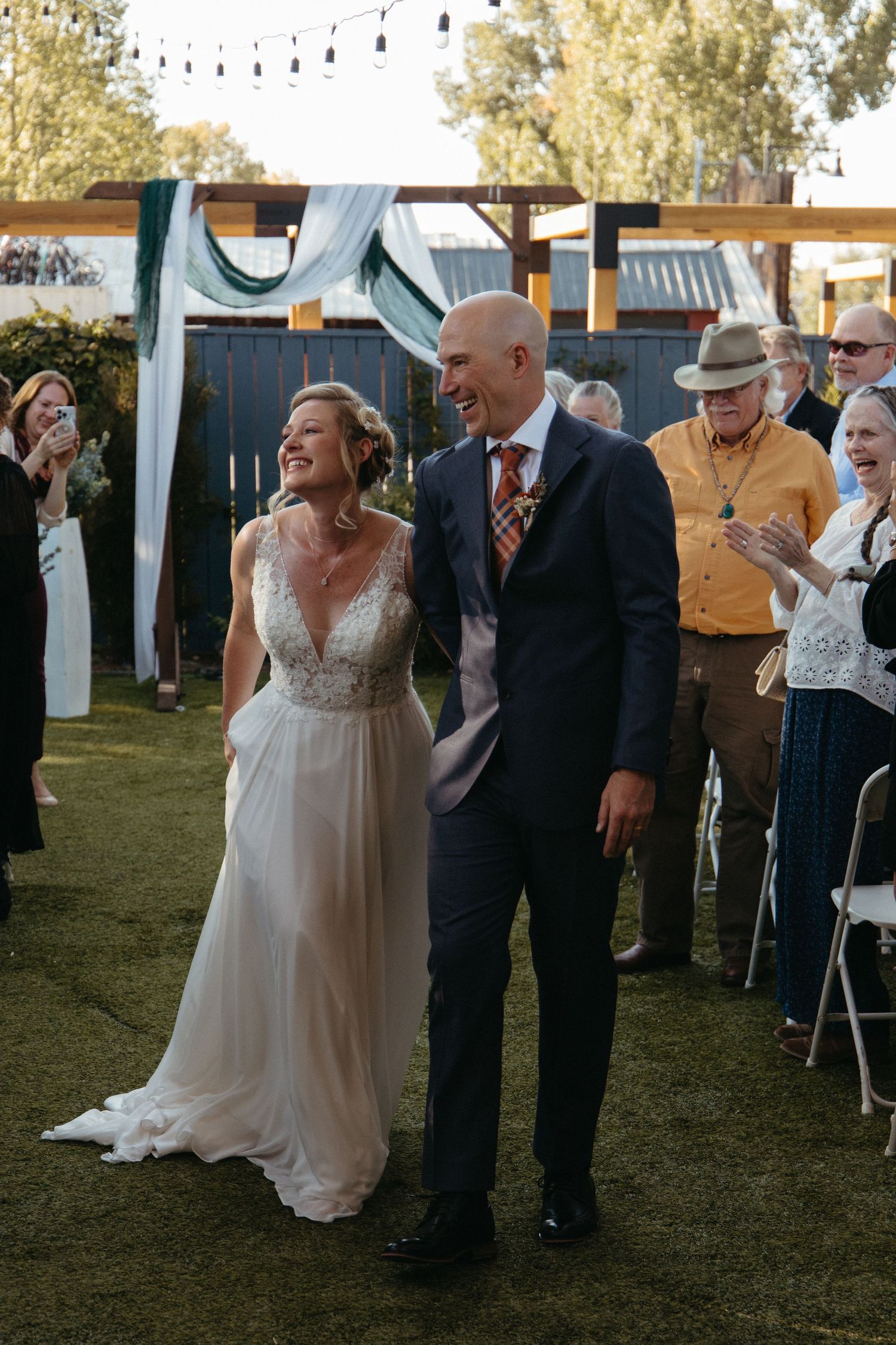 Wedding celebration on a lawn with string lights overhead and guests in the background.