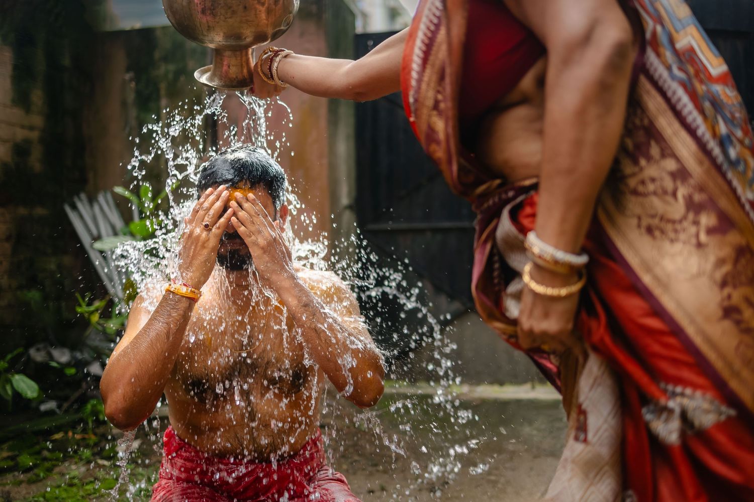 Traditional pre-wedding ritual with water being splashed in an outdoor setting.