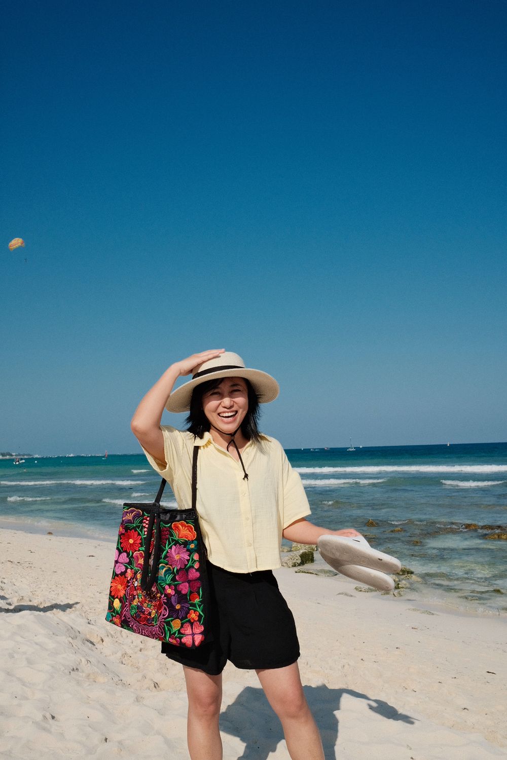 Woman in sun hat enjoying beach day with floral beach bag.