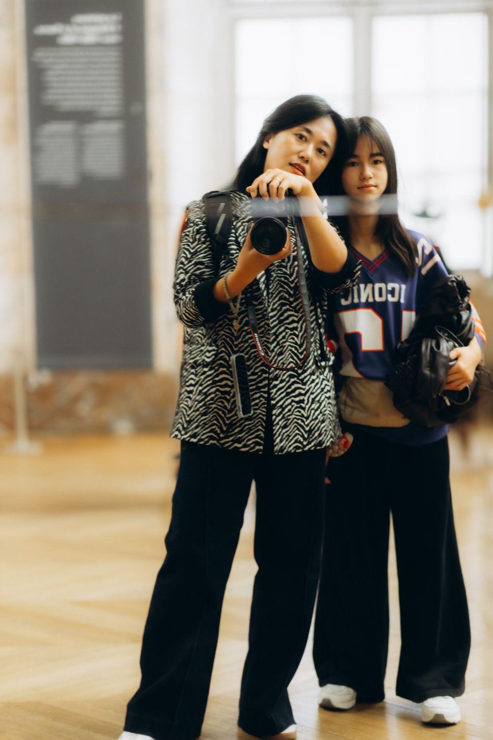 Three children in black outfits dance together in a bright studio space with wooden floors.