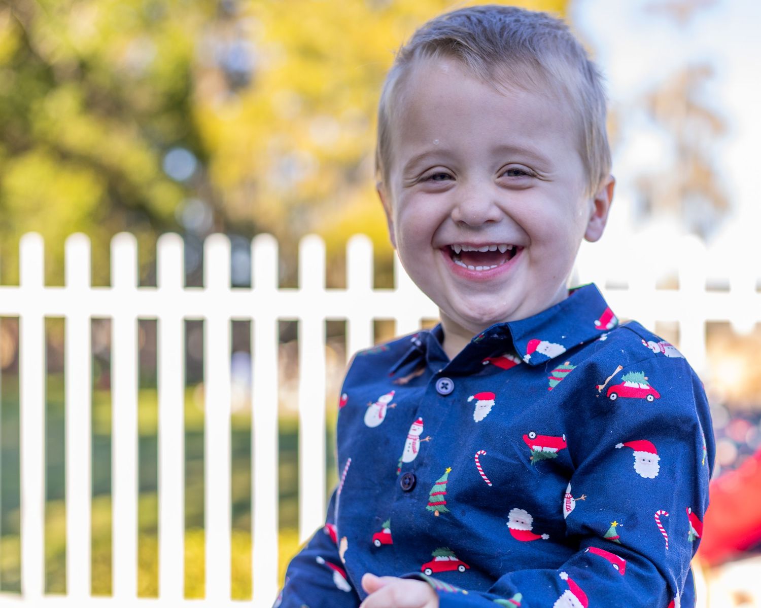 Happy young boy with Down syndrome smiling in a festive Christmas print shirt outdoors.