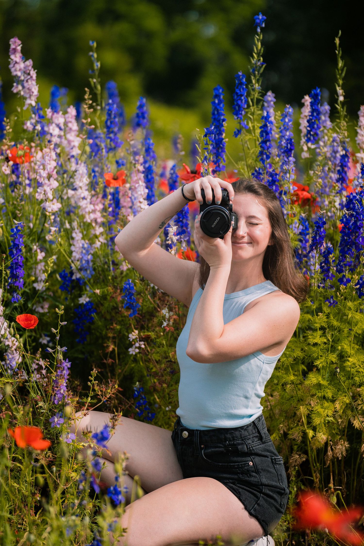 Photographer captures images among vibrant blue delphiniums and pink wildflowers.