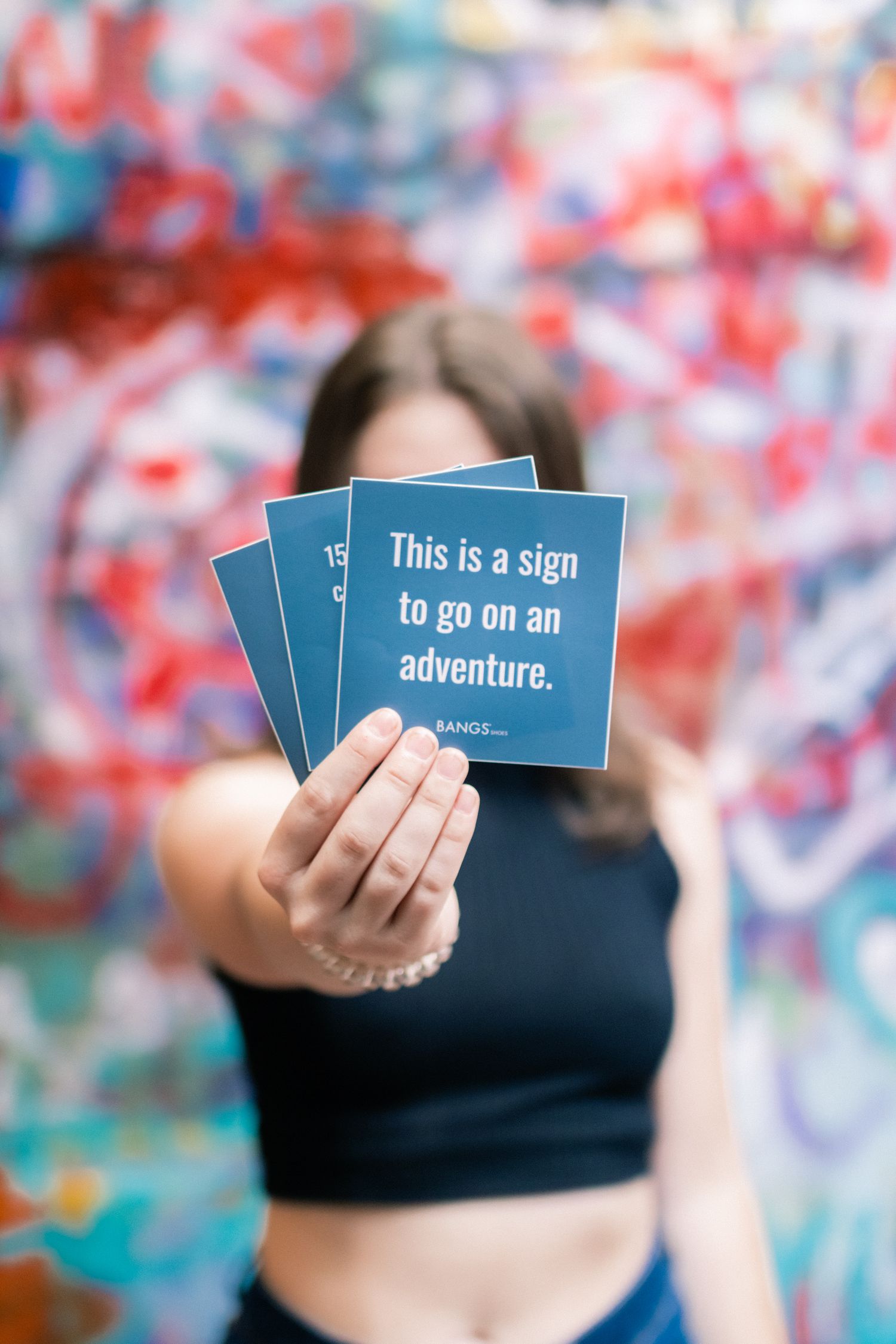 Hands hold up blue cards with inspirational text against a colorful blurred background.