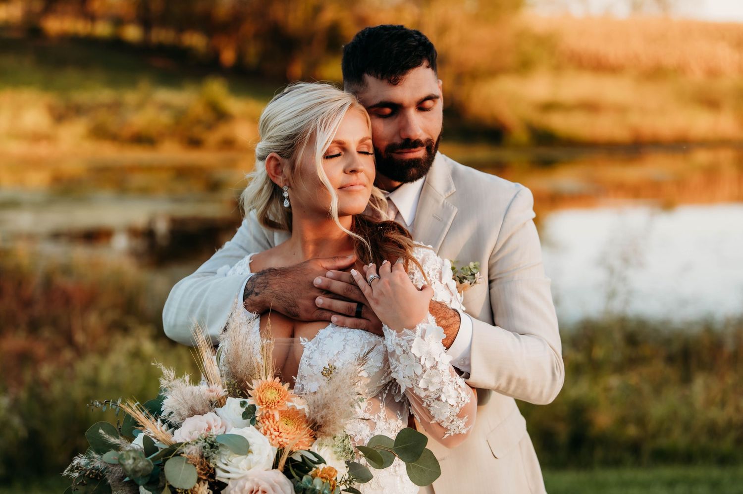 A tender moment between newlyweds holding a beautiful floral bouquet at golden hour.