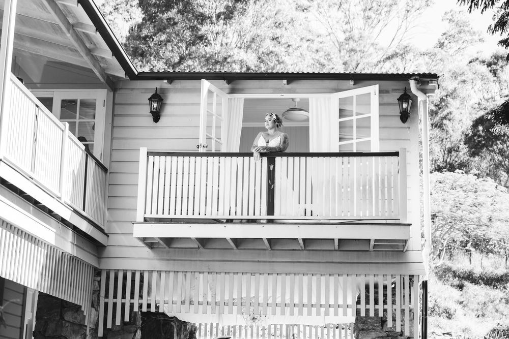 White multi-level house with attached garage features covered front porch and dark shutters on a landscaped property.