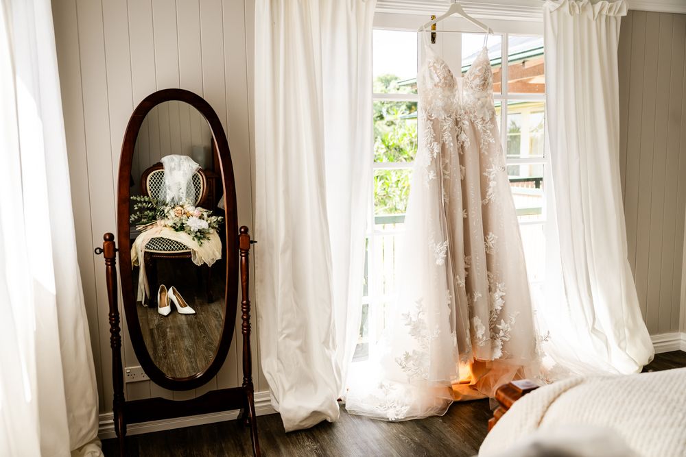 White sheer curtains blowing in the breeze through an open window next to a dark wood framed mirror.