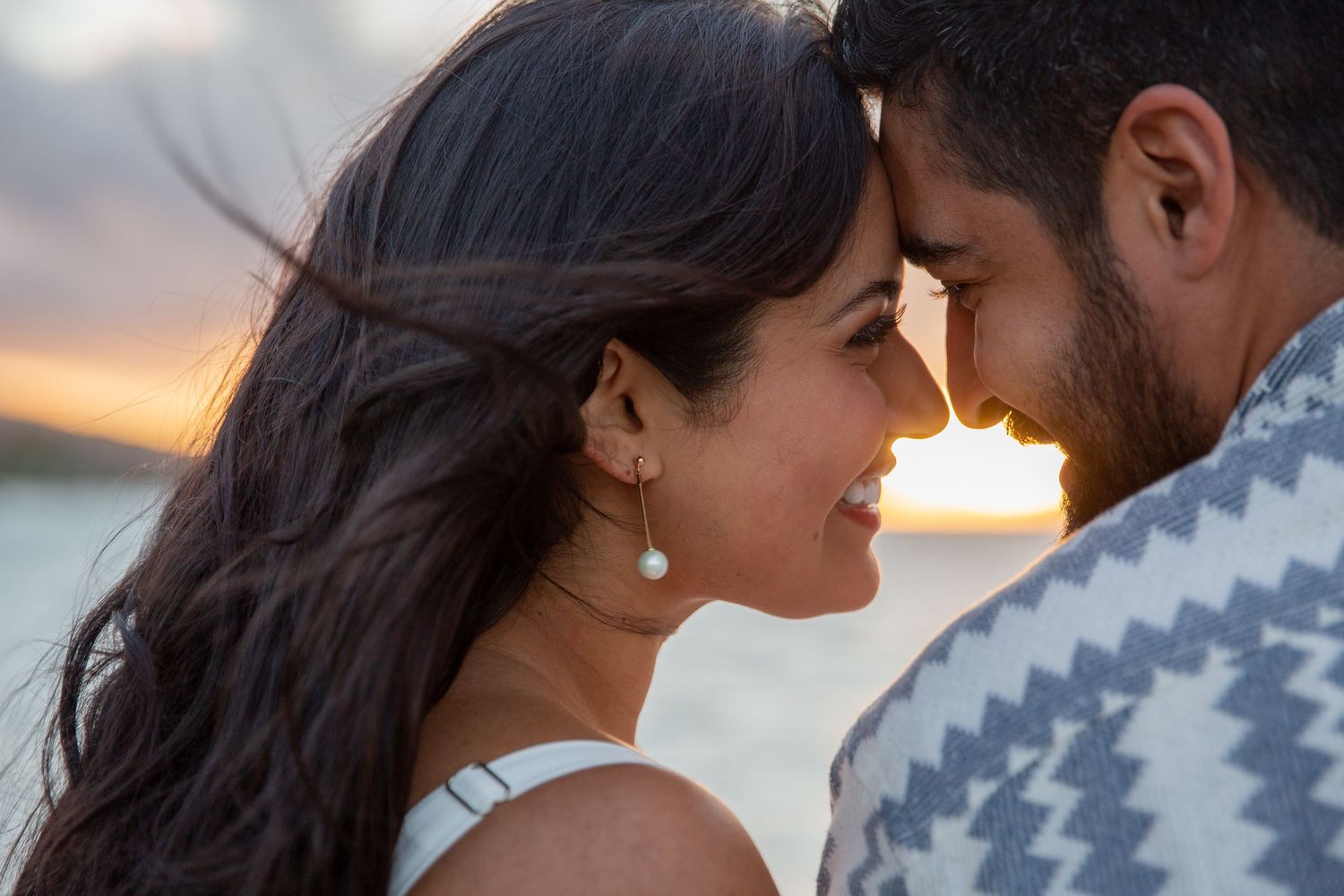 A romantic couple shares an intimate moment during a sunset photo session while wearing coordinated sweaters at Kahala Hotel.