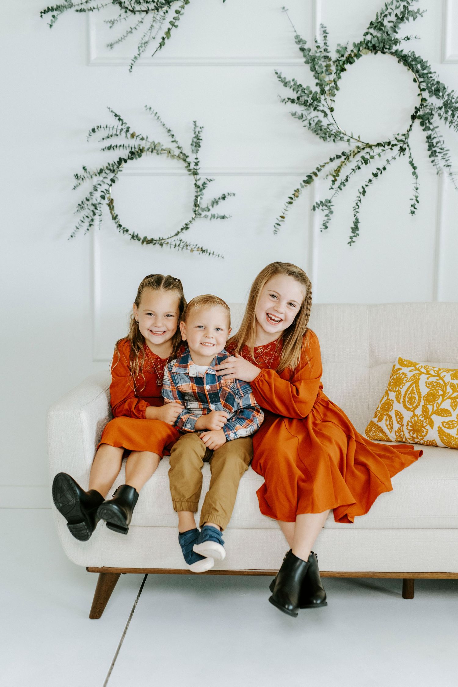 Three lifestyle photos show a relaxed family moment on a white couch with greenery decor and yellow accent pillows.