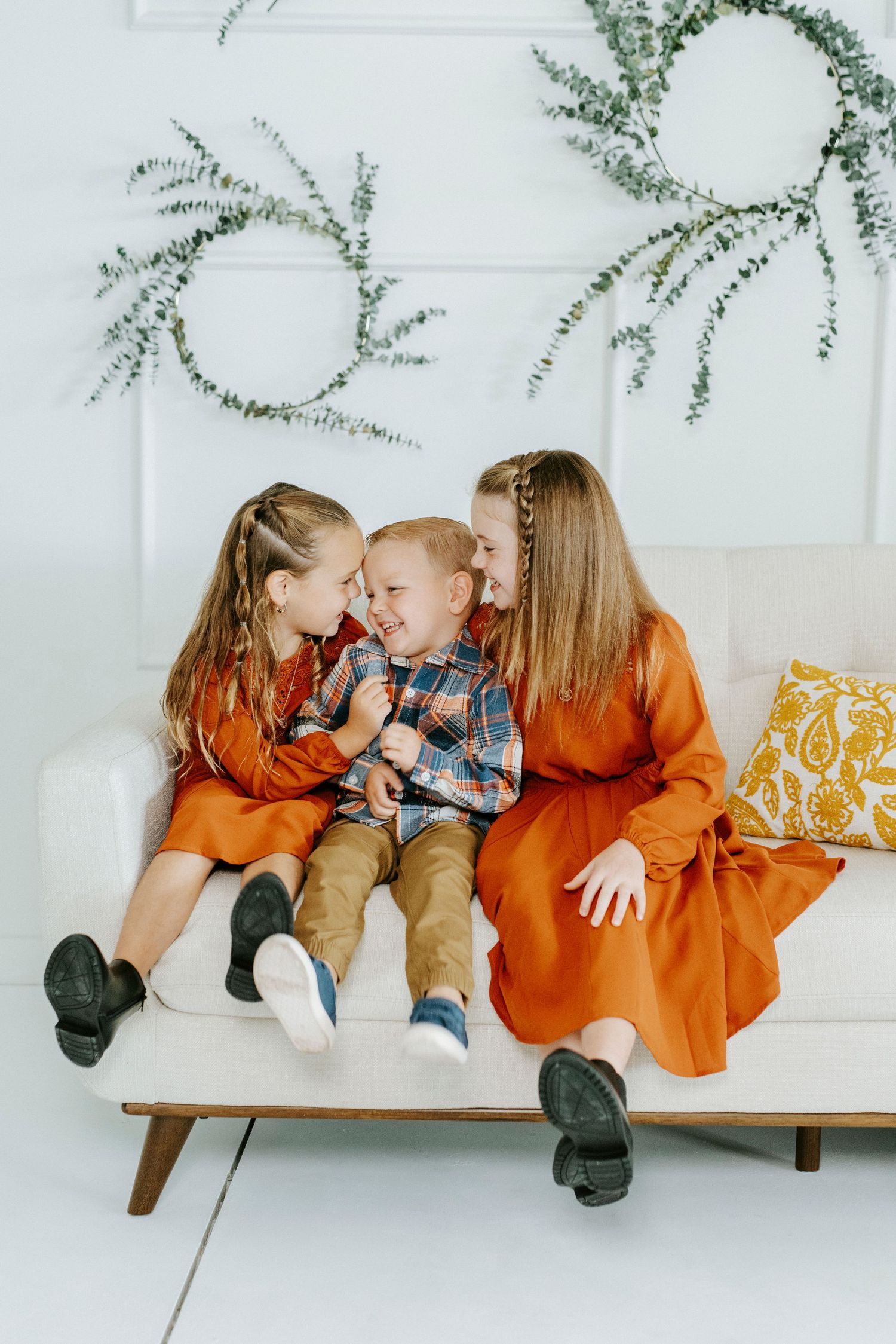 A family shares tender moments on a white bench with decorative greenery hanging above them.