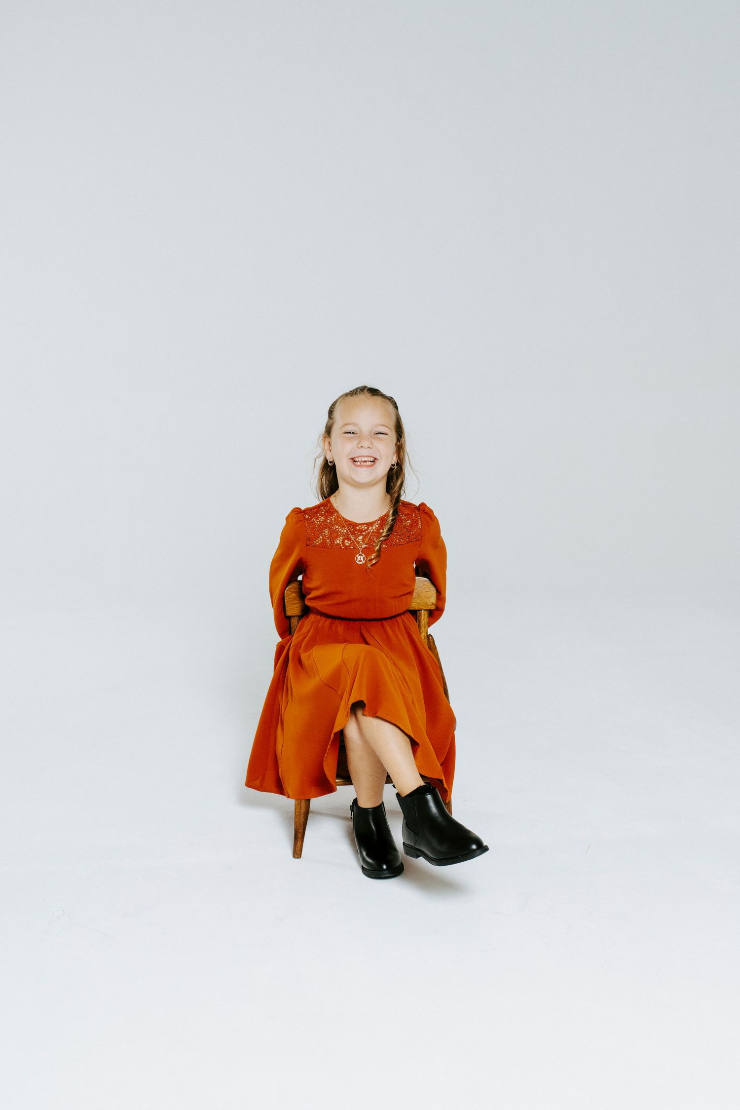 Sequence of three photos showing someone in a bright orange dress sitting on a white background.