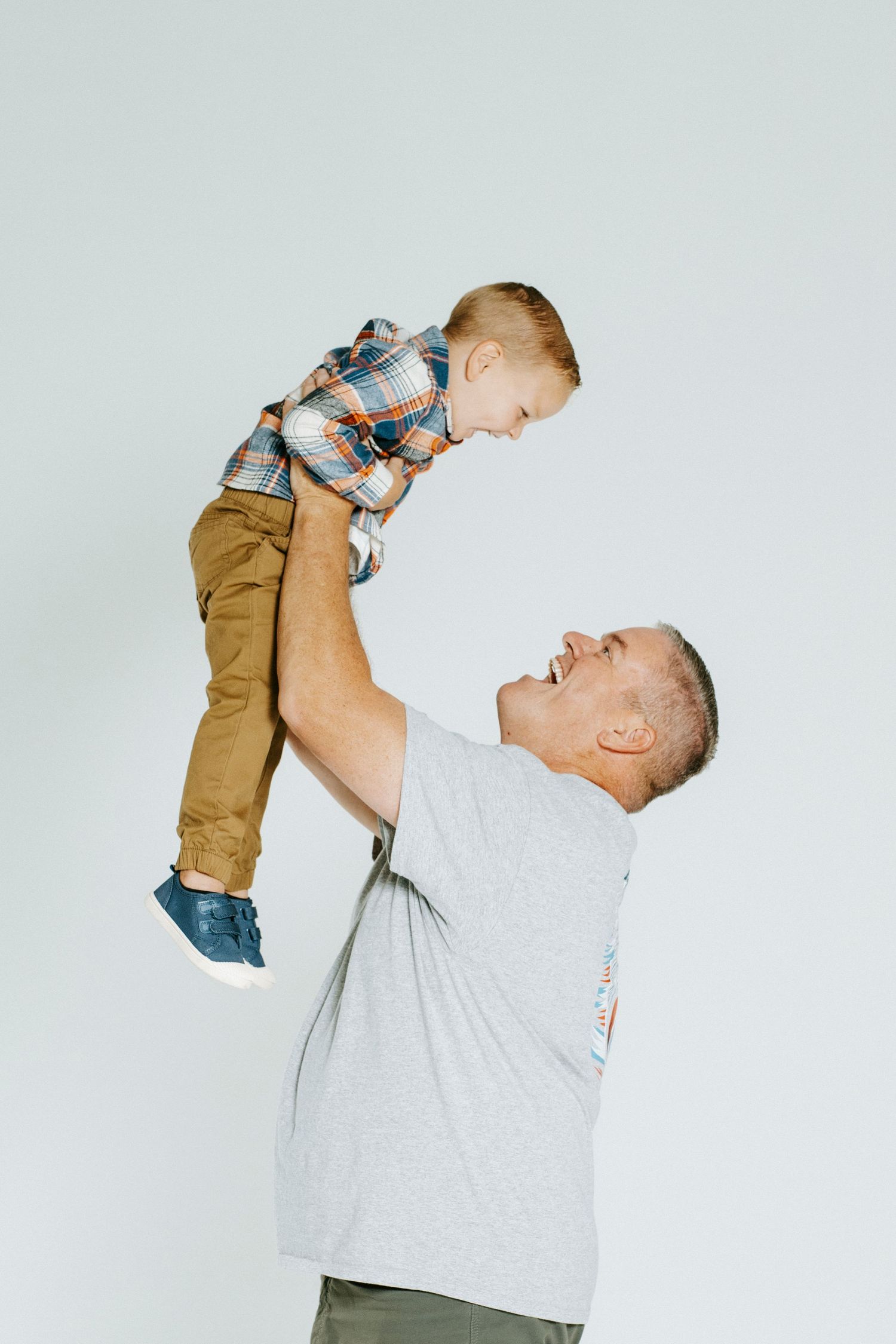 A joyful moment captured in a series of three photos showing playful lifting and interaction against a light background.