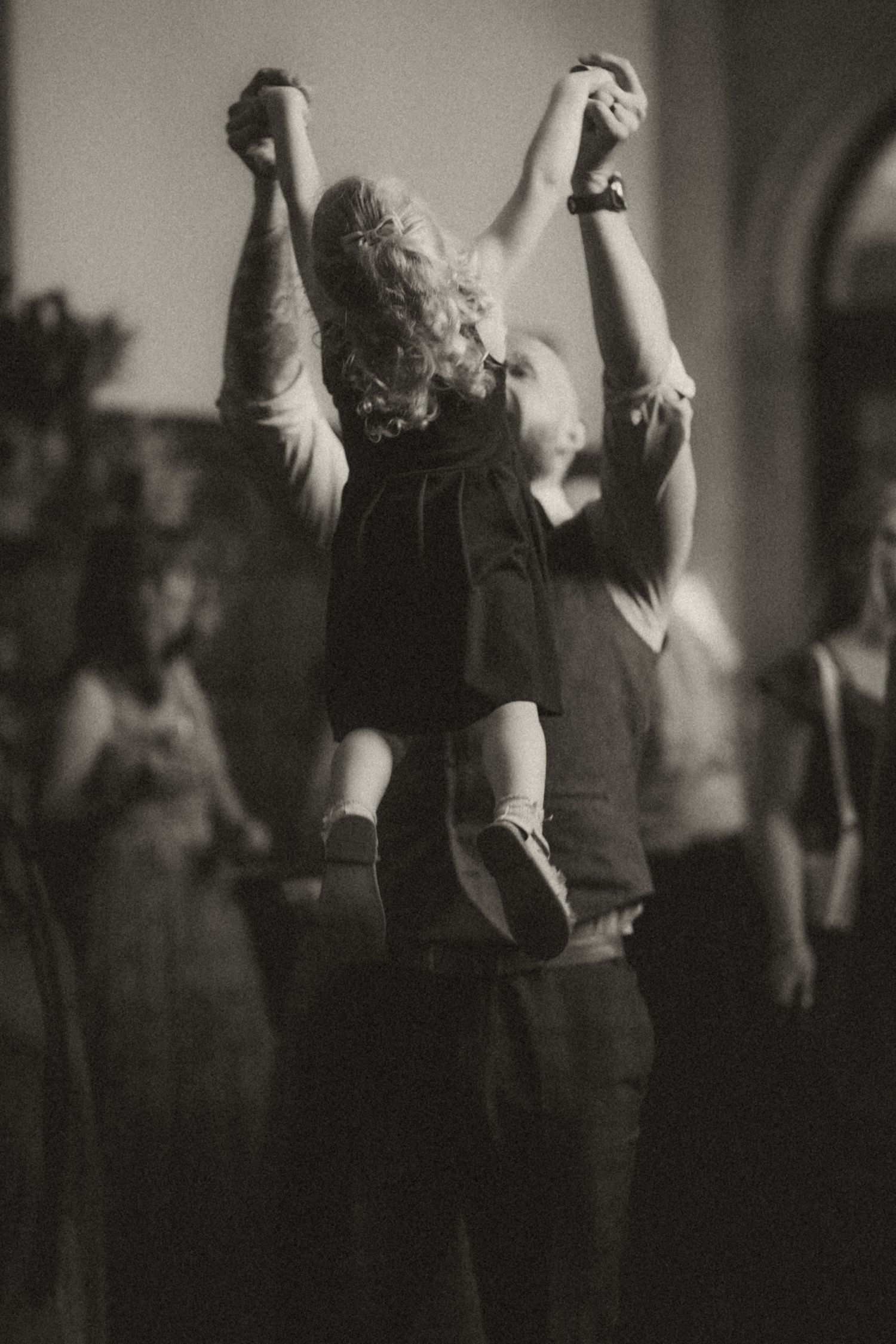 Black and white image of a crowd raising their arms during what appears to be a concert or music event.