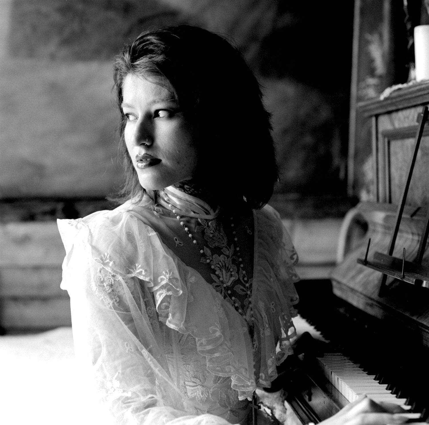Lady sat at the piano in a southern gothic white dress looking startled
