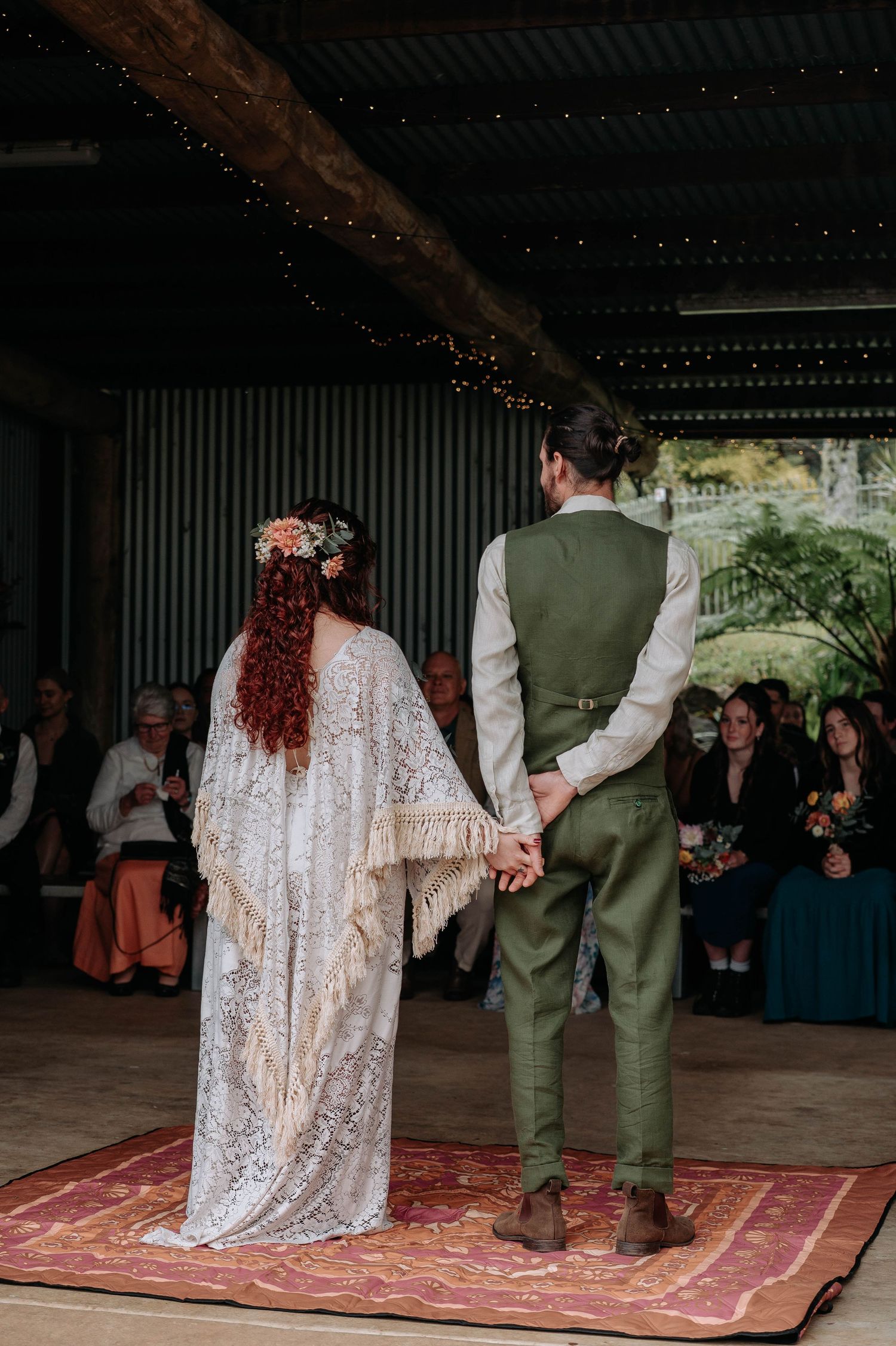 Couple dancing on a decorative red carpet during a rustic outdoor wedding reception.