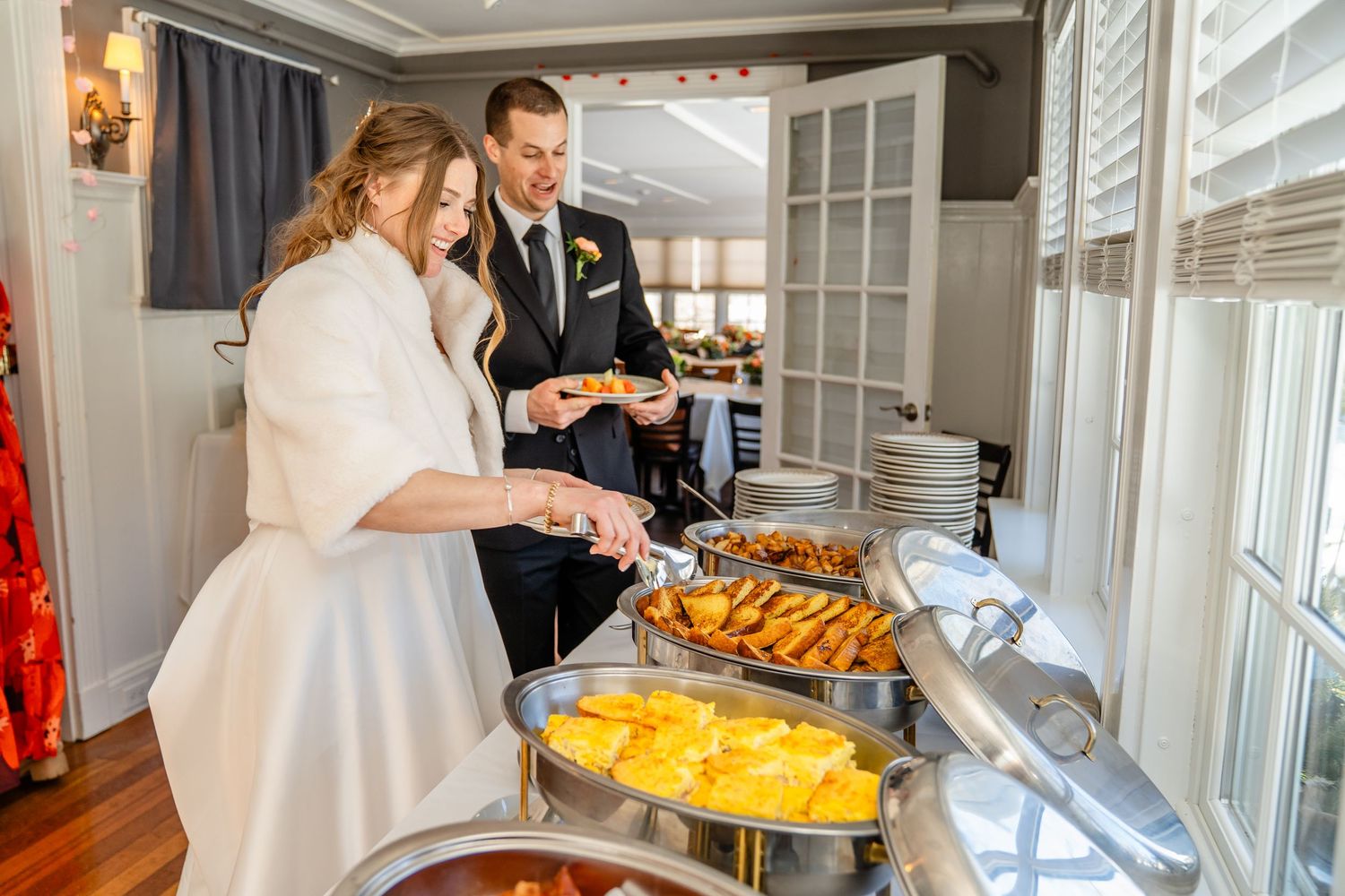 Wedding guests help themselves to a buffet spread of colorful foods and appetizers at an elegant venue.