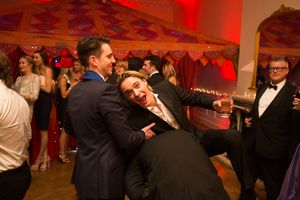 People dancing and having fun at a formal event with red mood lighting and festive atmosphere.