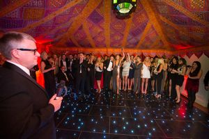 Panoramic view of a dimly lit ballroom with ornate decor, blue floor lights, and people gathered for an event.