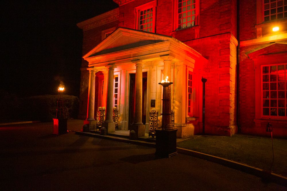Historic brick building illuminated in dramatic red lighting at night with multiple architectural features visible.