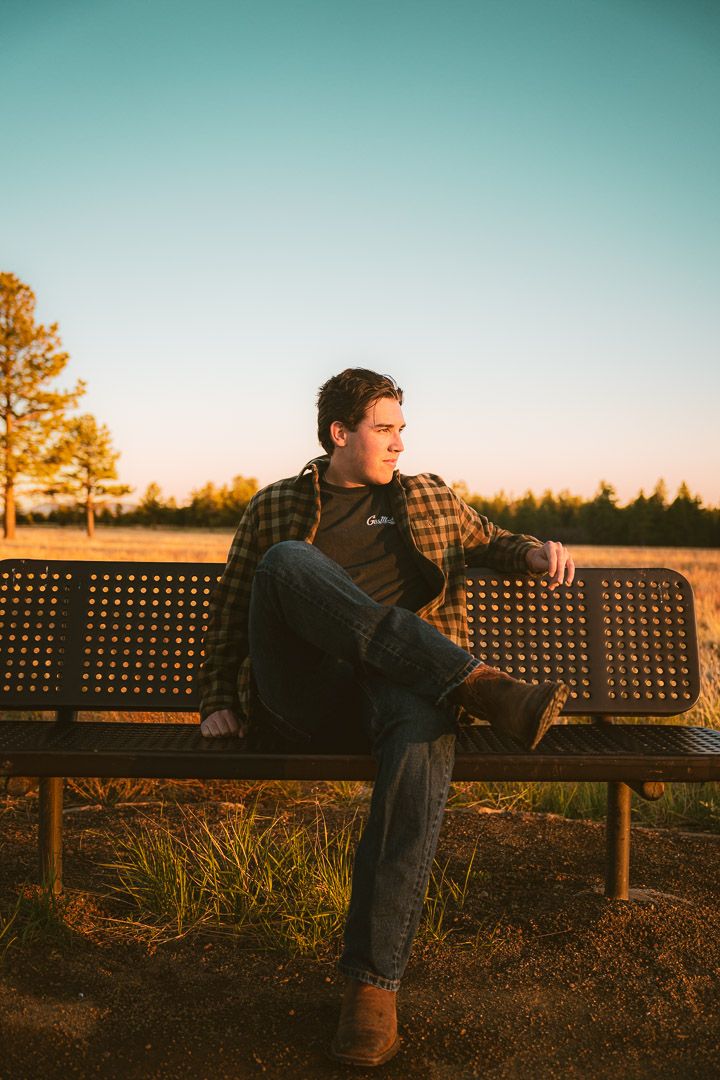 Person lounging on a park bench at sunset with golden light filtering through trees in the background.