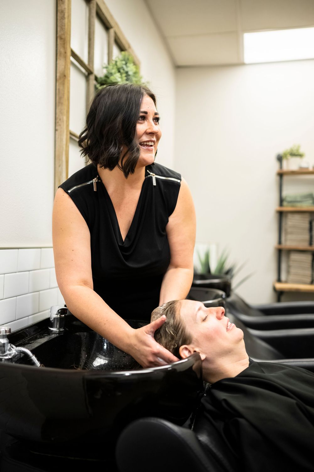 Hair salon treatment session with stylist washing client's hair.