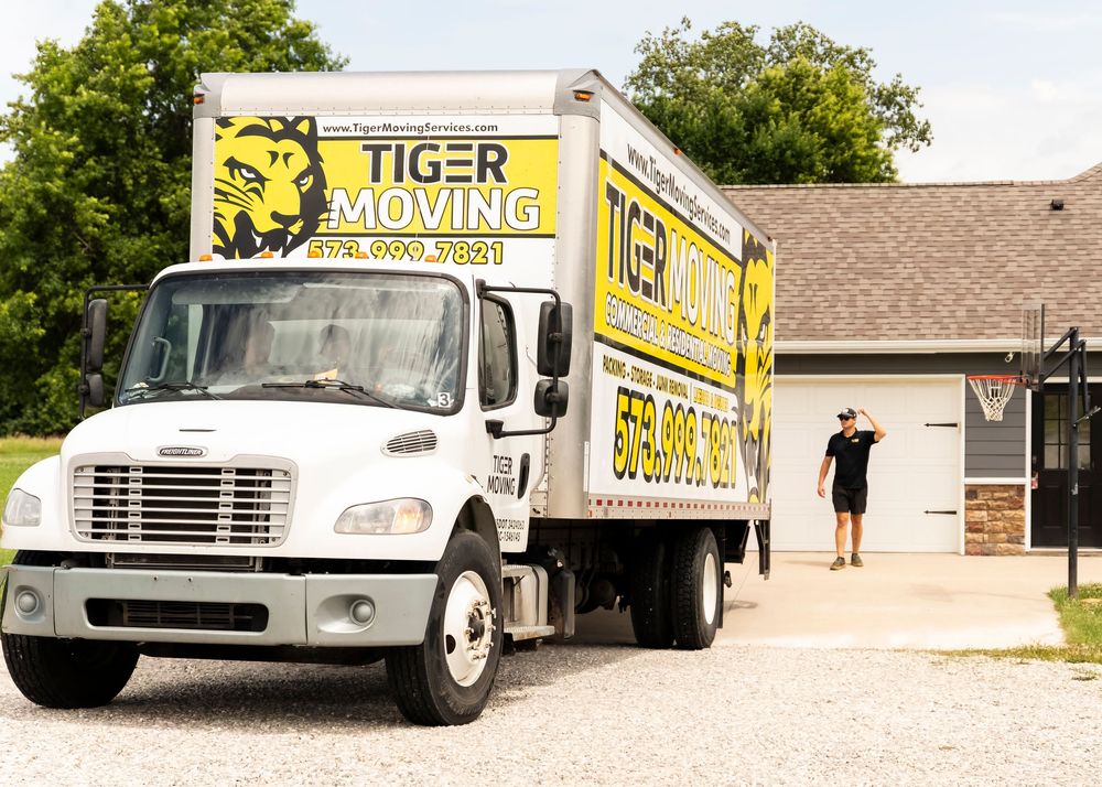 Fleet of yellow Tiger Moving company trucks lined up on a street.