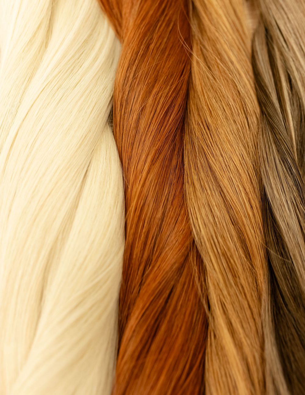 Collection of hair extensions in various shades from platinum blonde to warm brown.