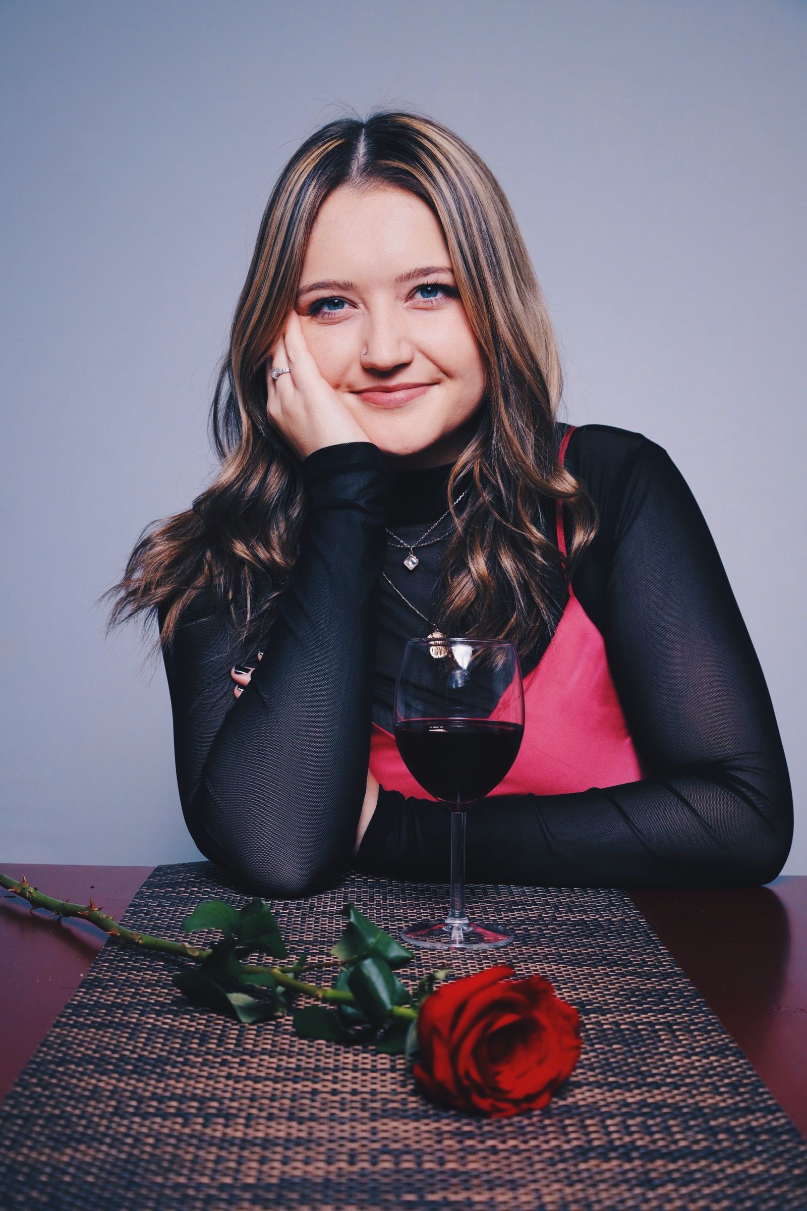 A moody portrait series with a red rose on a patterned tablecloth against a gray background.