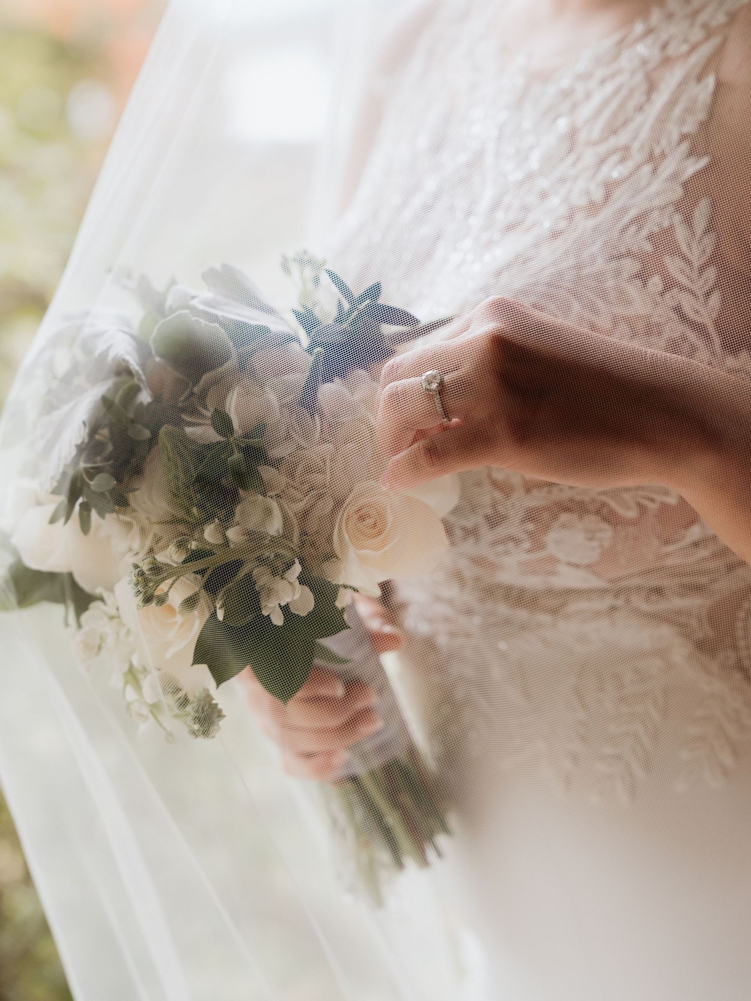 Close-up details of a white lace wedding dress with delicate floral bouquet accents.