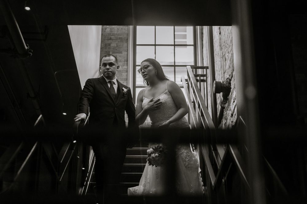 Black and white wedding photo series capturing intimate candid moments through window reflections.