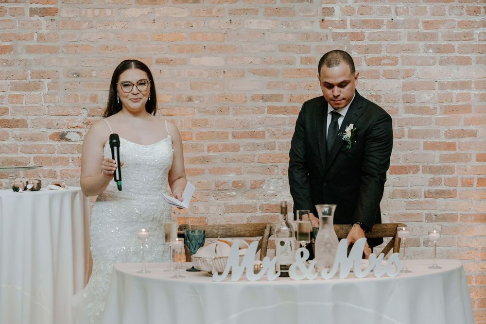 Wedding reception in an industrial brick venue with white tables and elegant decor.